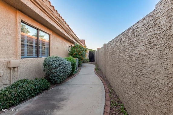 Side view of a house with textured walls and a landscaped walkway.