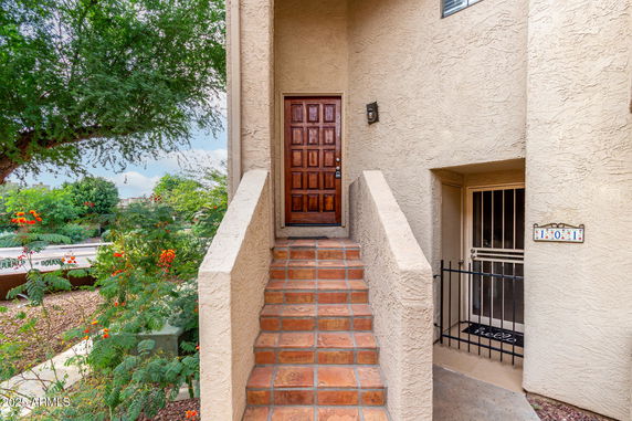 Entrance view of a house with a wooden door and steps leading up.