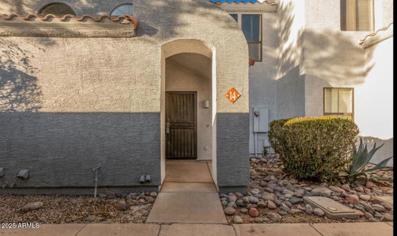 Front view of a house entry with arched doorway and adjacent window.