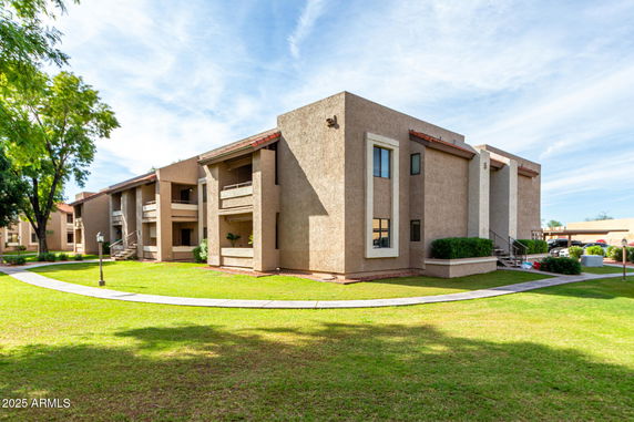 Front view of two-story apartment building with balconies and exterior stairs.