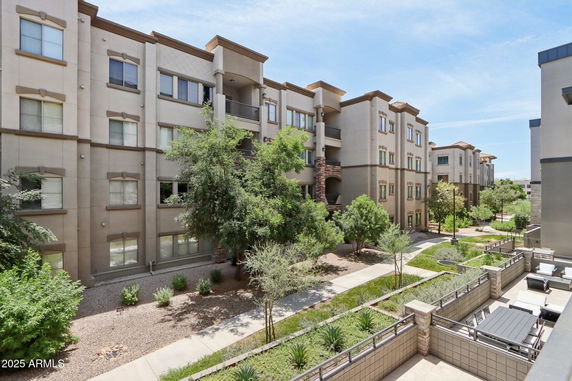 Front view of multi-story apartment buildings with pathways and landscaped greenery.