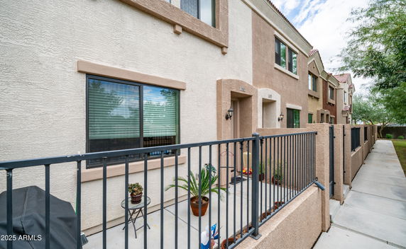 Front view of a multi-story townhouse with a small fenced outdoor area.