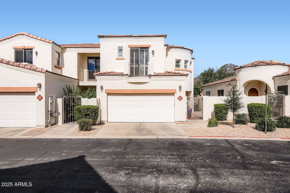 Front view of a two-story house with white stucco walls and a double garage.