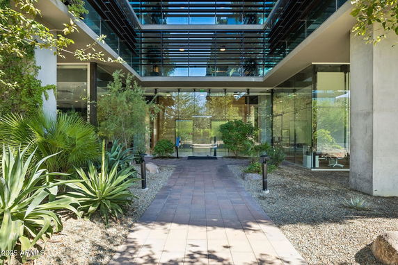Glass-fronted building entrance with modern architectural design and landscaping.
