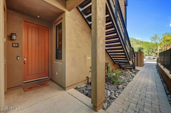 Entry view of a house with a wooden front door and external staircase.