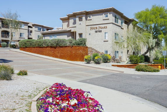 Front view of a multi-story building with a beige exterior and sloped driveway.