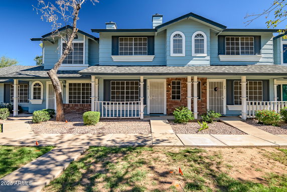 Front view of a two-story townhouse with a porch and white railings.