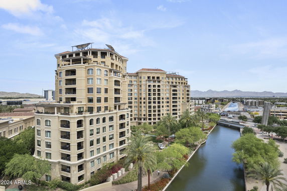 Front view of a multi-story apartment building with balconies and rooftop structures.