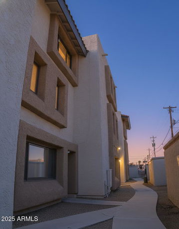 Side view of a multi-story building with prominent window frames and textured walls during dusk.