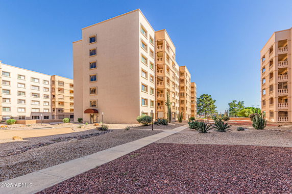 Front view of a multi-story residential building with a desert landscape.