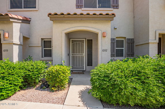 Front view of a townhouse with a covered entryway and a security screen door.