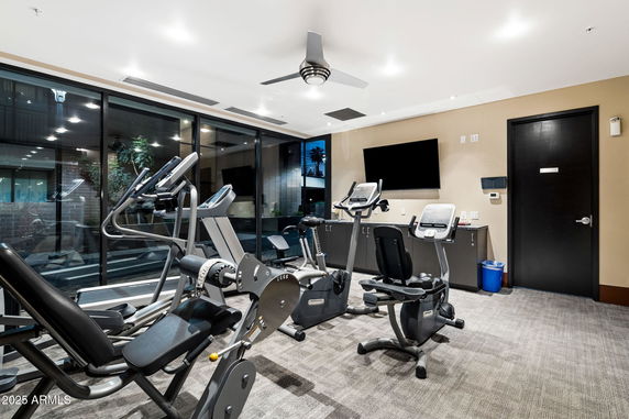 Room equipped with exercise machines and a wall-mounted TV.