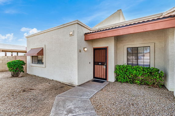 Front view of a single-story house with a textured exterior wall and a red door.