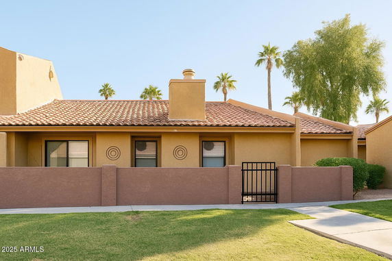Front view of a single-story house with a tiled roof and enclosed front yard.