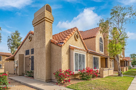 Front view of a house with a gabled roof and stucco exterior.