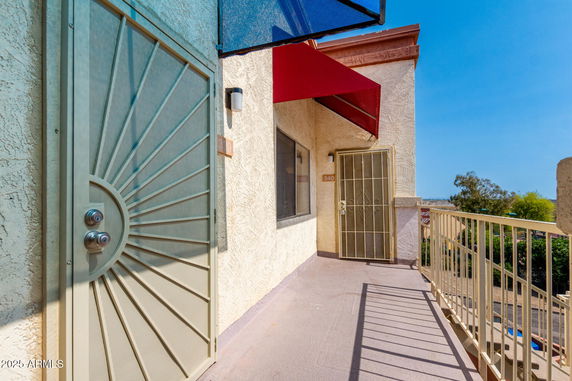 Front view of an outdoor apartment entrance with protective metal doors and colorful awnings.