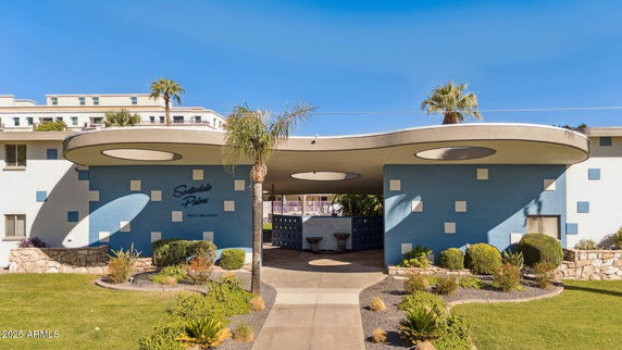 Front view of a modern building with a circular entrance and decorative landscaping.