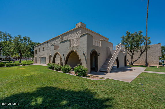 Front view of a two-story brick building with arched doorways and an exterior staircase.