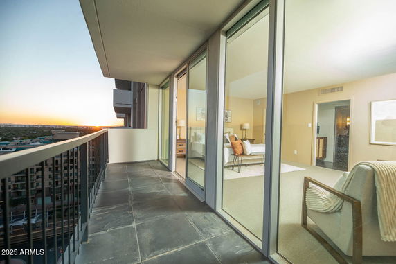Balcony with a view overlooking the city at sunset.