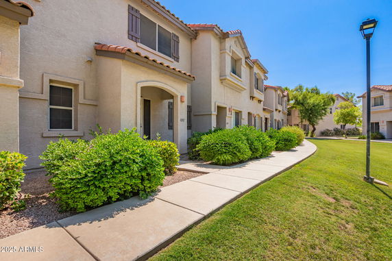 Front view of a row of two-story residential buildings with arched entrances and tiled roofs.