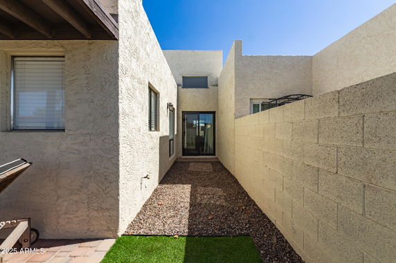 Side view of a modern house with textured walls and narrow gravel path.