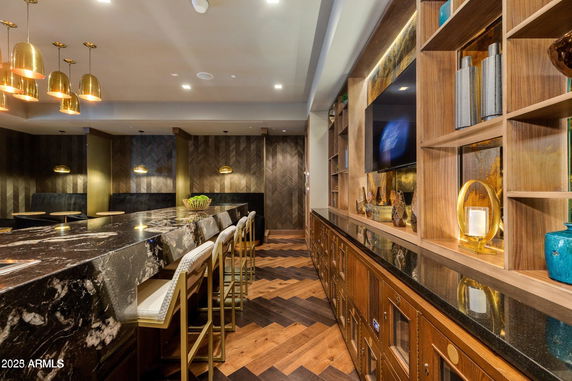 Interior view of a luxurious clubhouse with a marble bar counter, stylish lighting, and decorative shelving.