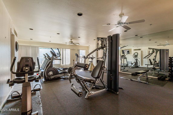 Indoor gym area with various fitness equipment and mirrored walls.