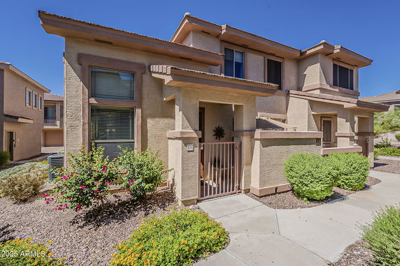 Front view of a two-story house with decorative window frames and a small gated entryway.