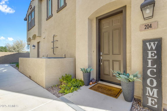 Front view of a house entrance with a welcome sign and potted plants.