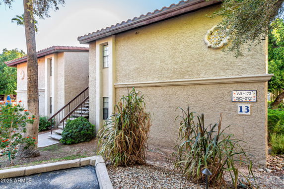 Front view of a two-story residential building with exterior stairs and a tiled roof.
