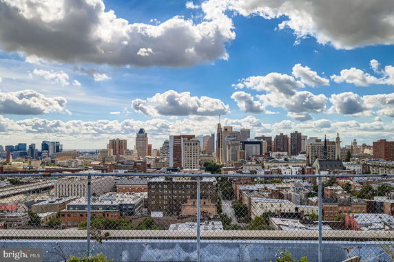Panoramic view of a city skyline with various buildings under a partly cloudy sky.