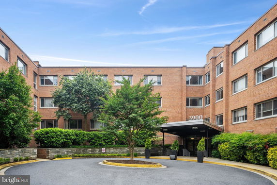 Front view of a multi-story brick building with numerous windows and a canopy entrance.