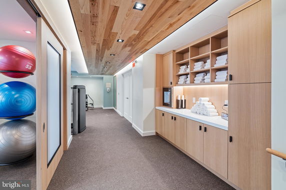 Interior view of a modern gym area with exercise equipment and storage shelves for towels.