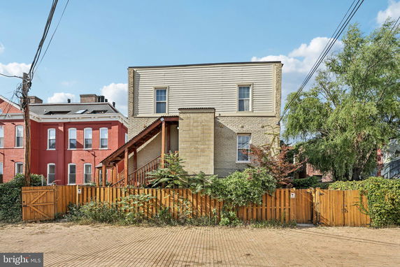 Front view of a multi-story house with a wooden fence.
