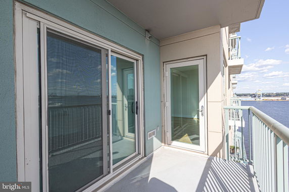 Balcony view overlooking water with sliding glass doors and railing.