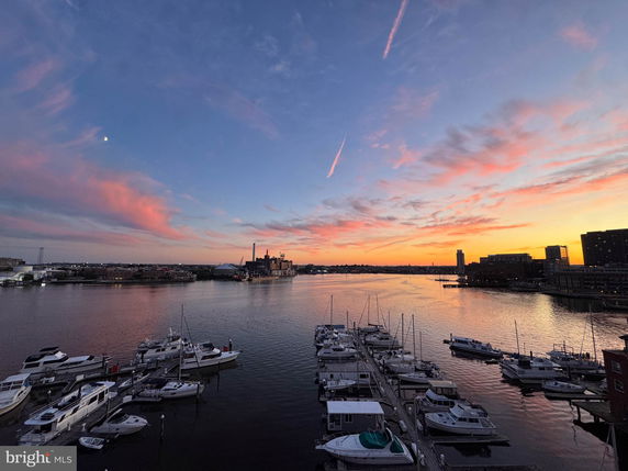 Panoramic view of harbor with boats and a sunset sky.