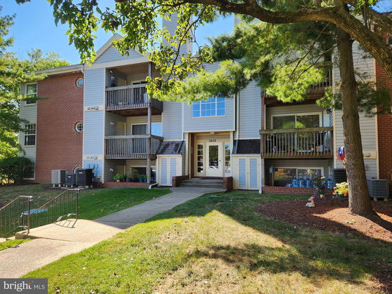 Front view of a multi-story residential building with balconies and brick accents.