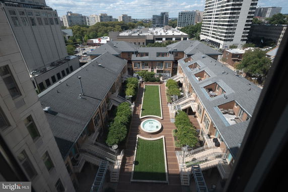 Aerial view of a courtyard surrounded by multi-story buildings with a central green area and fountain.
