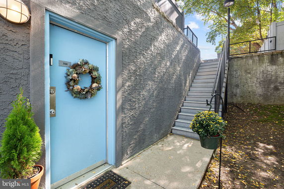 Front view of a gray building entrance with a blue door and external staircase.