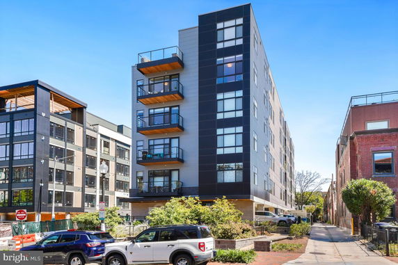 Front view of a modern multi-story apartment building with balconies.