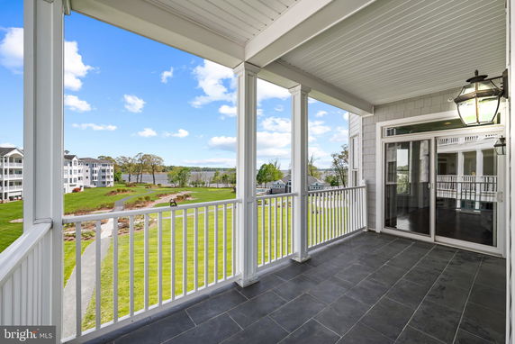 Balcony view from a building overlooking expansive green lawns and nearby structures.