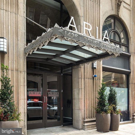 Front view of a building entrance with a decorative canopy and large glass doors.