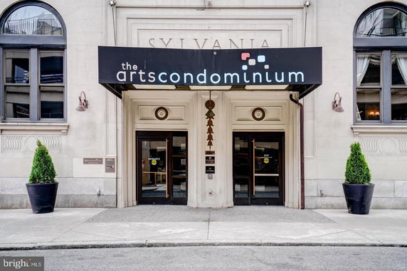 Front view of a condominium building entrance with double doors and decorative signage.