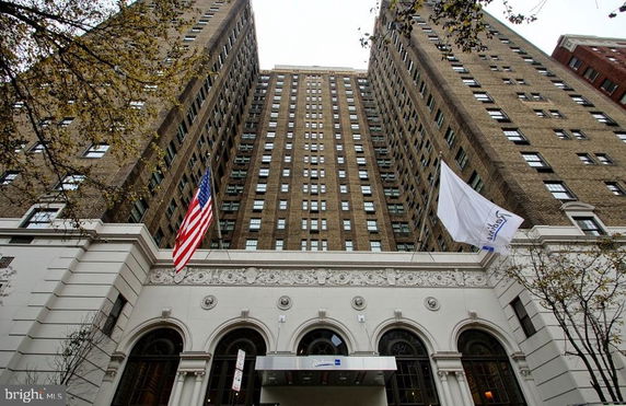 Front view of a tall multi-story building with flags and arched entrances.