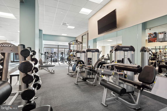 Interior view of a gym with exercise machines and free weights.