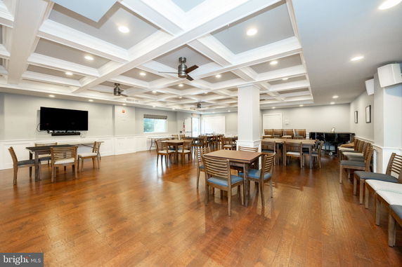 Interior view of a common area for recreation activities with tables, chairs, and a mounted TV.