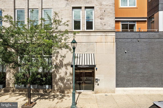 Front view of a multi-story building with brick and stone facade and an awning over the entrance.
