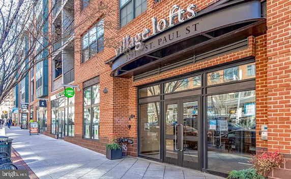 Front view of a brick building with large glass doors and signage above.