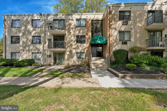Front view of a multi-story building with balconies and an entrance canopy.