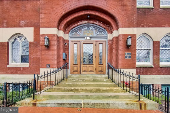 Front entrance of a brick building with arched doorway and steps.